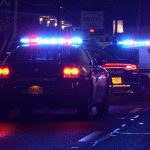 Police cars with flashing lights at nighttime.