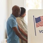 People voting at polling booths with American flag.