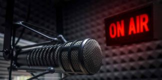 Microphone in soundproof studio with "On Air" sign.