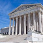 U.S. Supreme Court building with statues and columns.