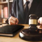 Gavel judges hand glasses and book on desk