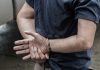 Person in handcuffs standing with crossed wrists