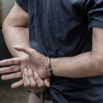 Person in handcuffs standing with crossed wrists