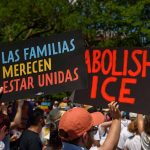 People holding protest signs outdoors against ICE policies
