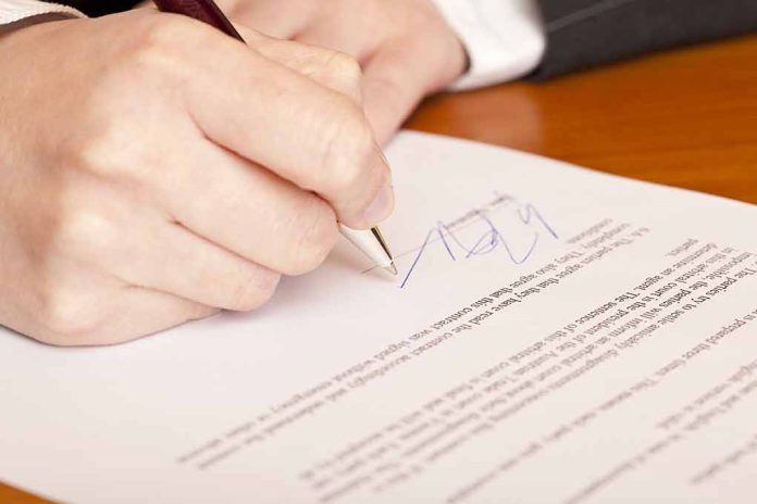 66092728 featured image Hand signing a document on a wooden table
