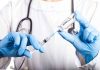 Doctor filling syringe with vaccine from vial