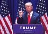 Man speaking at podium with USA flags behind him