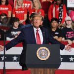 Person speaking at podium with crowd behind them