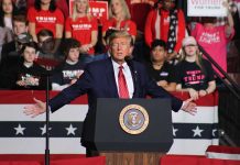 Person speaking at podium with crowd behind them