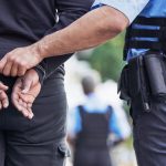 Police officer handcuffing person outdoors