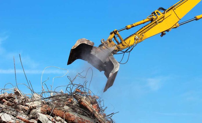 249527200 featured image Excavator demolishing rubble against a blue sky.