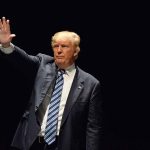 Man in a suit waving against dark background