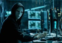 Person wearing mask and hoodie at computer desk