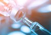 Syringe needle drawing liquid from vial