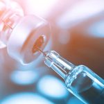 Syringe needle drawing liquid from vial