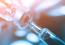 Syringe needle drawing liquid from vial