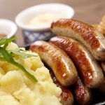 Sausages mashed potatoes sauerkraut and sauces on plate