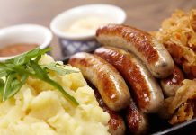 Sausages mashed potatoes sauerkraut and sauces on plate