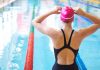 Swimmer adjusting cap near an indoor pool