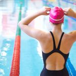 Swimmer adjusting cap near an indoor pool