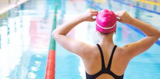 Swimmer adjusting cap near an indoor pool
