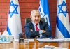Man sitting at desk with Israel flags behind him