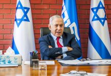 Man sitting at desk with Israel flags behind him
