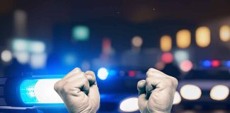 Hands in handcuffs in front of police cars