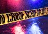 Yellow crime scene tape with police lights in background