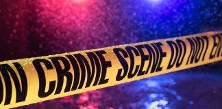 Yellow crime scene tape with police lights in background