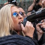 Woman shouting into megaphone while in a crowd.