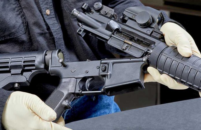 1088730455 Person assembling a rifle with gloved hands