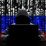 Hacker in hoodie with Russian flag background and code