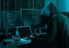 Hacker in dark room surrounded by computer screens
