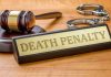 Gavel, handcuffs, and Death Penalty sign on desk.