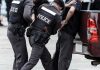 Police officers arresting a handcuffed person.