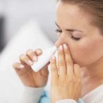 Woman applying nasal spray for relief