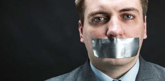 Man in business attire with duct tape over his mouth, conveying a message about silence