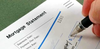 A person writing a check on a mortgage statement