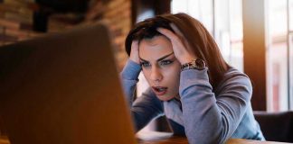 Woman frustrated at laptop, holding her head.