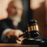 Judge using gavel in a courtroom setting.
