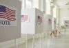 Voting booths with American flag and VOTE signs.