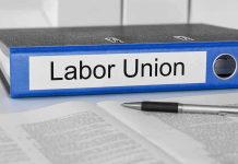 A black binder labeled Labor Union placed on a desk with papers and a pen