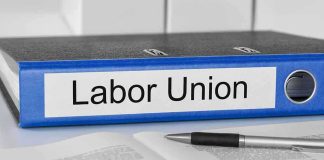 A black binder labeled Labor Union placed on a desk with papers and a pen