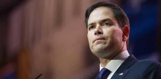 Man in suit speaking at podium.