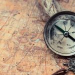 Old compass on a vintage map background.