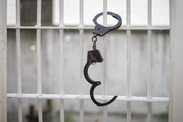 680970664 Handcuffs hanging on white metal bars