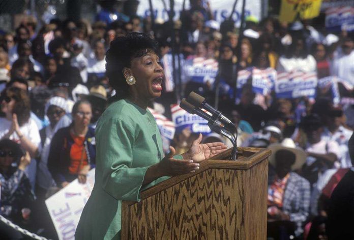shutterstock_107319632.jpg A woman passionately speaking at a political rally in front of a large crowd