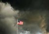American flag waving against a dark, stormy sky
