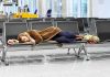Airlines Revolt: Demand Action Amid Travel Chaos! A traveler sleeping on a bench in an airport waiting area